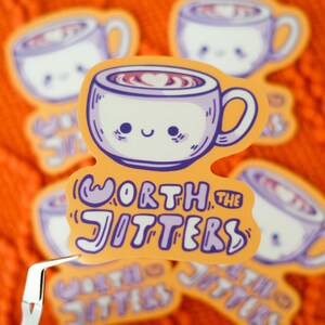 May include: A sticker featuring a cute cartoon coffee cup with a heart-shaped design in the coffee. The sticker has the text "Worth the Jitters" in purple and white on an orange background. Several stickers are visible.