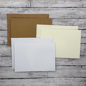 May include: Three envelopes stacked on top of each other. The top envelope is cream colored, the middle envelope is white, and the bottom envelope is brown.