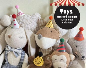 Pode incluir: Uma coleção de brinquedos de pelúcia, incluindo um coelho, uma raposa, um urso e um macaco, cada um usando um pequeno chapéu de festa. Os chapéus são decorados com bolinhas, listras e as palavras "Happy Birthday". A imagem também inclui o texto "Toys, Stuffed Animals, Little Hats, Kids Fun!"