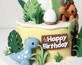 May include: A two-tiered cake decorated with a dinosaur theme. The cake features a light yellow base, white frosting, and various dinosaur-themed decorations, including a blue dinosaur, a brown dinosaur, and a sign that says "Happy Birthday".