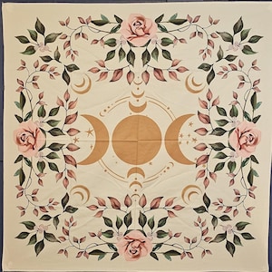 Può includere: Un arazzo color crema con un designo di fasi lunari dorate e rose rosa. L'arazzo presenta tre lune dorate, stelle e un motivo circolare. Le rose sono disposte attorno ai bordi dell'arazzo.