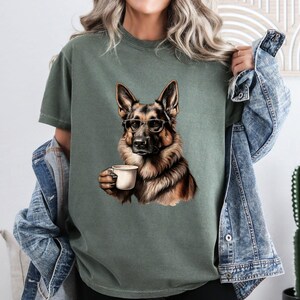 Puede incluir: Una camiseta verde con una imagen de dibujos animados de un perro pastor alem&aacute;n con gafas y sosteniendo una taza de caf&eacute;.