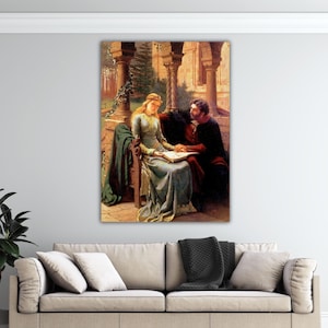 May include: A vertical wall art print depicting a historical scene with a woman in a long, light blue gown and a man in dark clothing sitting together on a stone bench, holding an open book between them under a stone archway with columns.