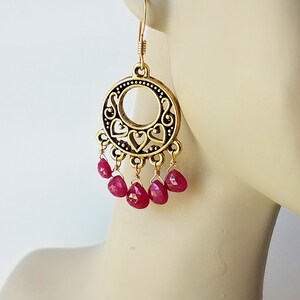 May include: Gold filigree earrings with a dangling cluster of red gemstone drops.