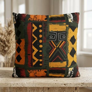 May include: A square throw pillow featuring a multi-colored geometric pattern with vertical bands of black, dark green, mustard yellow, and burnt orange. The design includes repeating triangles, circles, diamonds, and abstract linear motifs.