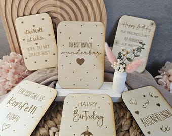May include: Six wooden cards with different birthday greetings. The cards are decorated with hearts, dots, and a cupcake graphic. The text on the cards includes "Happy Birthday", "Du bist einfach wunderbar", "Die Welt ist schön, weil du mit drauf bist", "Für dich soll es Konfetti regnen", and "Busenfreundin".