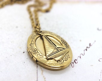 sailboat. oval locket necklace. in gold ox