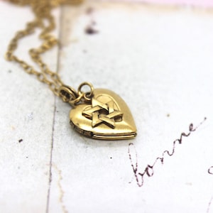 May include: A gold heart-shaped locket necklace with a Star of David charm. The locket is open and the chain is visible.