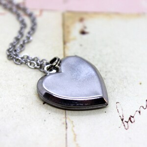May include: A silver heart-shaped locket necklace with a chain.