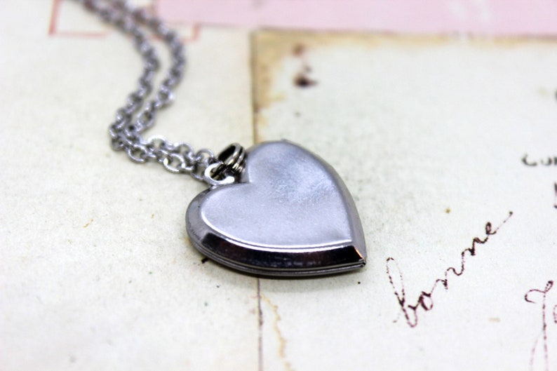 May include: A silver heart-shaped locket necklace with a chain.