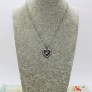 May include: A silver chain necklace with a heart-shaped pendant featuring a bat design.