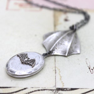 winged bat. oval locket necklace. silver ox jewelry with silver tone bat and wing pendant