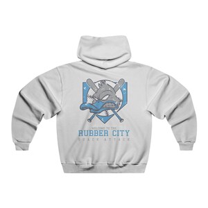 Può includere: Felpa con cappuccio bianca con una grafica blu e grigia di un'anatra con mazze da baseball incrociate e un piatto da baseball. Il testo "Welcome to the Rubber City Quack Attack" è stampato sotto la grafica.