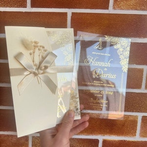 Elegante gouden transparante trouwkaart met bloemenprint, crème envelop en satijnen lint, doorzichtige acryluitnodiging, aangepaste uitnodiging