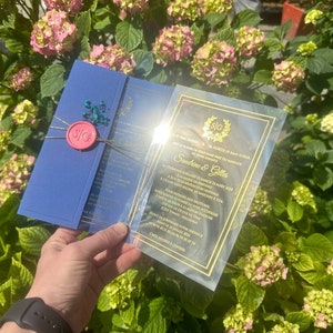 Elegante gouden bloemenprint transparante huwelijksuitnodiging met crèmekleurige envelop en satijnen lint, doorzichtige acryl huwelijksuitnodiging
