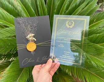 Könnte beinhalten: Zwei Hochzeitseinladungen, eine mit schwarzem Hintergrund und goldenen Akzenten, die andere mit transparentem Hintergrund und goldenen Akzenten. Die Einladungen zeigen die Namen des Paares, "Claus & Jhalen", und das Datum der Hochzeit, "19.10.2024".