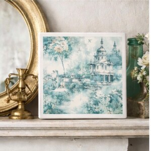 May include: A square ceramic tile featuring a blue and white toile-style print of a multi-tiered pagoda structure surrounded by lush foliage and trees. The design is rendered in soft, watercolor-like shades of teal and white on a smooth surface.