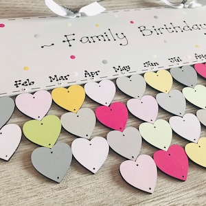 May include: A white wooden board with the text "Family Birthdays" and a calendar with months of the year.  Each month has a row of colorful wooden hearts.