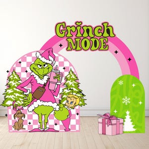 May include: A whimsical Christmas-themed display featuring the Grinch in a pink outfit, holding a drink, and a child. The words "Grinch MODE" are in green and yellow. A pink rainbow and gift box complete the festive scene.