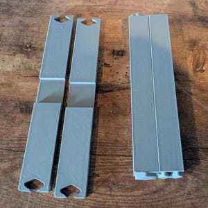 May include: Two sets of gray plastic dividers for organizing shelves. Each set has three pieces that can be connected to create a custom divider.