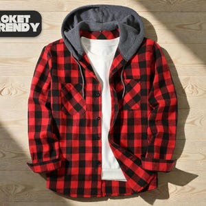 Puede incluir: Una camisa de franela a cuadros rojos y negros con capucha gris y camiseta interior blanca. La camisa tiene dos bolsillos en el pecho y está abotonada. El texto "JACKET TRENDY" está en un rectángulo negro en la esquina superior izquierda.