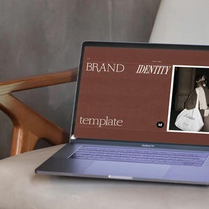 May include: A laptop displaying a brand identity template with the words "BRAND IDENTITY template" in white font on a brown background. The laptop has a purple keyboard and is on a white chair.