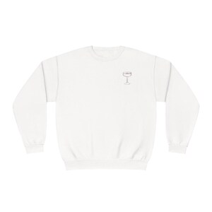May include: White crewneck sweatshirt with a simple line drawing of a champagne flute on the front.
