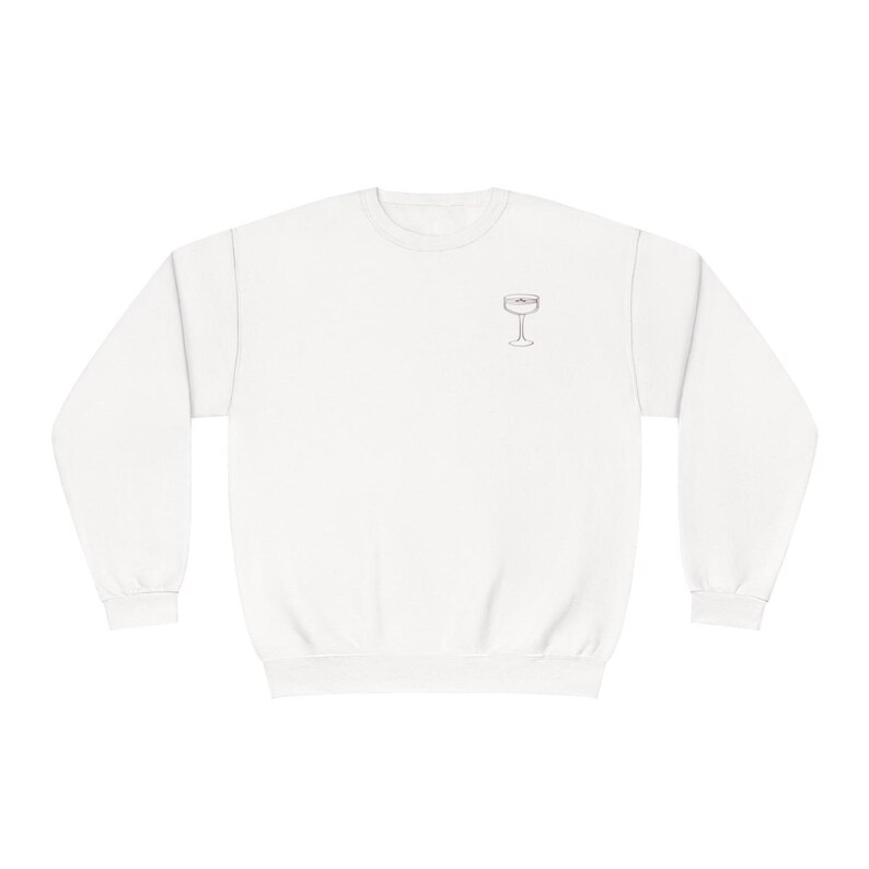 May include: White crewneck sweatshirt with a simple line drawing of a champagne flute on the front.