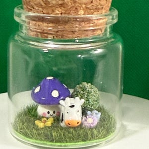 May include: A glass jar with a cork lid contains a miniature scene with a purple and white mushroom, a white cow figurine, and green grass.