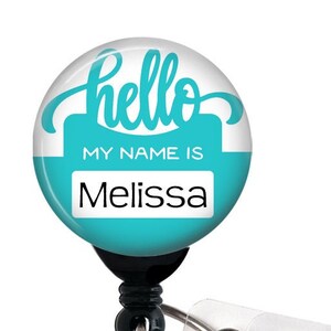 May include: A turquoise blue retractable badge holder with a white background and the text "hello" in a cursive font. The badge holder also has a white rectangle with the text "MY NAME IS" and the name "Melissa" in black text.