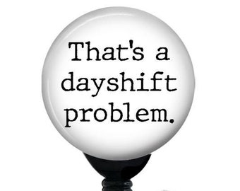 May include: White retractable badge holder with a black clip and a round white button that says "That's a dayshift problem."
