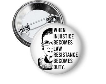 May include: A white button with a black and white image of Ruth Bader Ginsburg and the text "When injustice becomes law, resistance becomes duty."