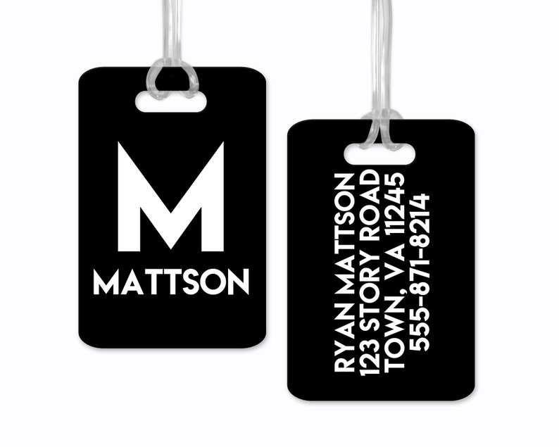 Może przedstawiać: Dwie czarne metki bagażowe z białym tekstem. Pierwsza metka ma dużą białą literę M i nazwisko Mattson. Druga metka zawiera imię i nazwisko Ryan Mattson, adres i numer telefonu.