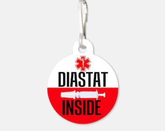 May include: A round, white and red medical alert tag with a silver clasp. The tag features the text "DIASTAT INSIDE" in black, a red medical symbol, and a syringe illustration.