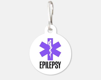 May include: A white round zipper pull with a purple star of life medical symbol and the word "EPILEPSY" in black text.