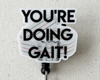 May include: A white and red striped retractable badge holder with the text "You're doing gait!" in black. The badge holder is attached to a black retractable cord and a silver metal ring.