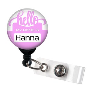 May include: Pink retractable badge holder with a white background and the text "hello my name is Hanna".