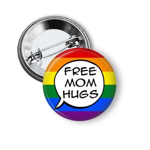 May include: A rainbow-colored button with a white speech bubble that says "FREE MOM HUGS".