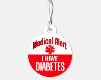 May include: White and red round medical alert tag with a silver clip. The tag has a red star of life symbol and the text "Medical Alert I Have Diabetes".