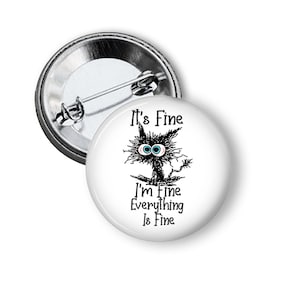 May include: A white button with a black and white cartoon cat with the text "It's Fine I'm Fine Everything Is Fine"