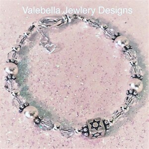 May include: A silver charm bracelet with clear crystal beads, white pearl beads, and a silver charm in the shape of a Star of David.