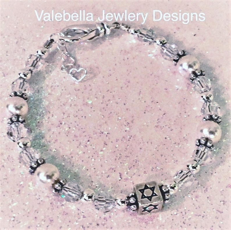 May include: A silver charm bracelet with clear crystal beads, white pearl beads, and a silver charm in the shape of a Star of David.