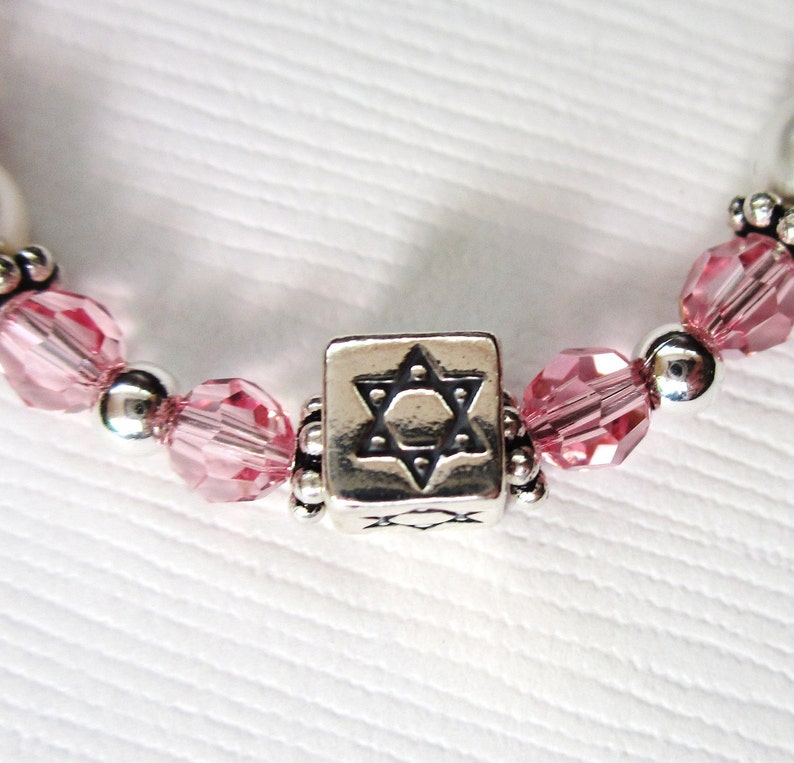 May include: A silver charm bracelet with pink crystal beads and a silver charm featuring a Star of David.