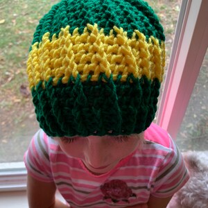May include: A green and yellow crocheted beanie hat. The hat has a wide yellow band around the middle.