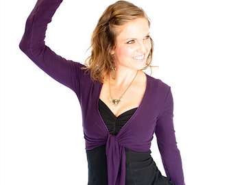 May include: A purple long-sleeved wrap top with a deep V-neckline. The top is tied at the waist and has a relaxed fit.