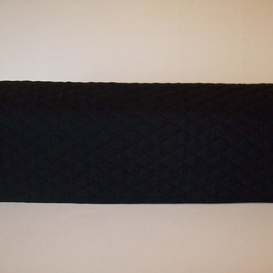 May include: A black, quilted, rectangular cover with rounded edges. The cover has a diamond pattern and appears to be made of a soft fabric. The item is designed to protect or cover an object.