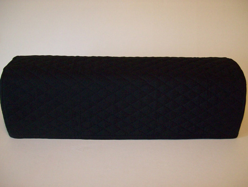 May include: A black, quilted, rectangular cover with rounded edges. The cover has a diamond pattern and appears to be made of a soft fabric. The item is designed to protect or cover an object.