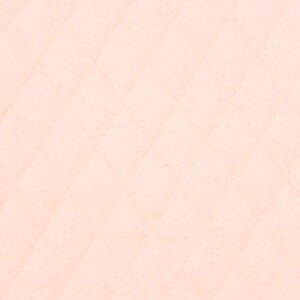 May include: A close-up of a quilted fabric in a soft peach color. The fabric has a diamond pattern created by the stitching. The texture appears smooth and slightly textured, with subtle variations in tone.