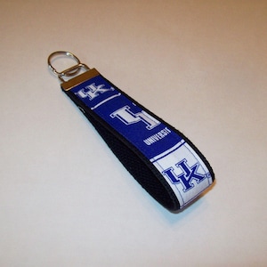 May include: A blue and white key chain with the text "University of Kentucky" and the letters "UK" in a white circle.