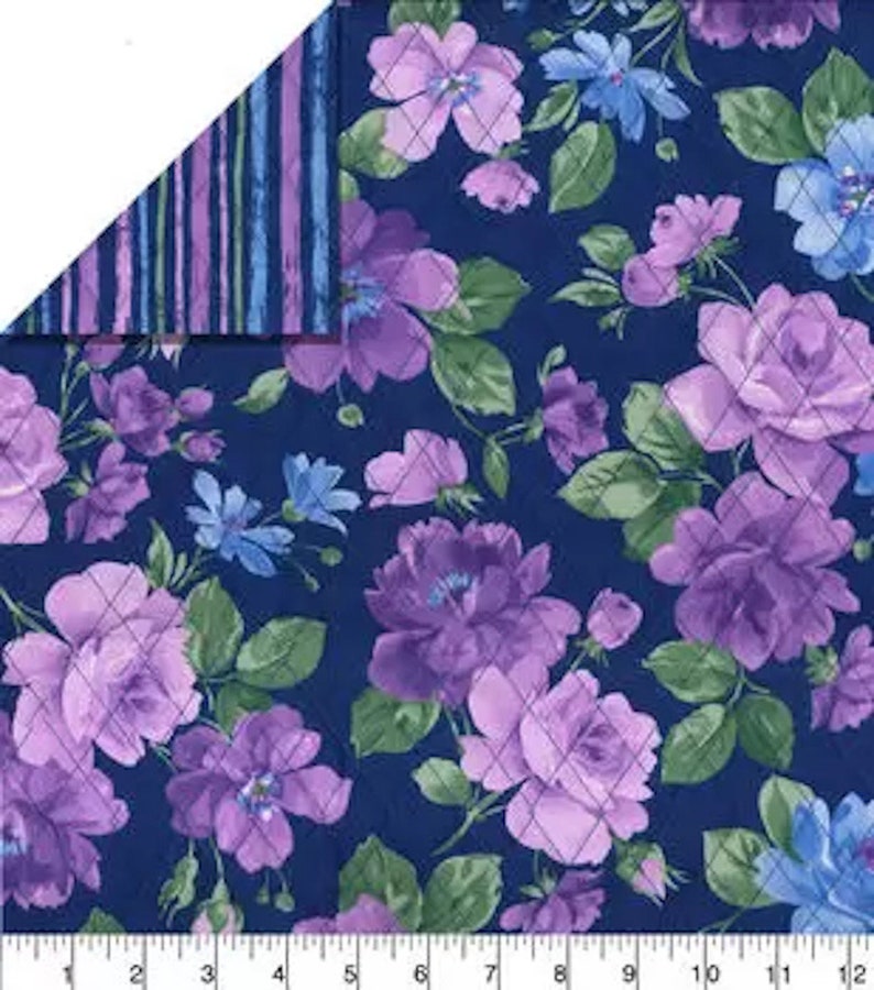 May include: A floral fabric featuring large purple roses and smaller blue flowers on a navy blue background. The design includes green leaves and a quilted pattern. The reverse side has vertical stripes in shades of blue and purple.